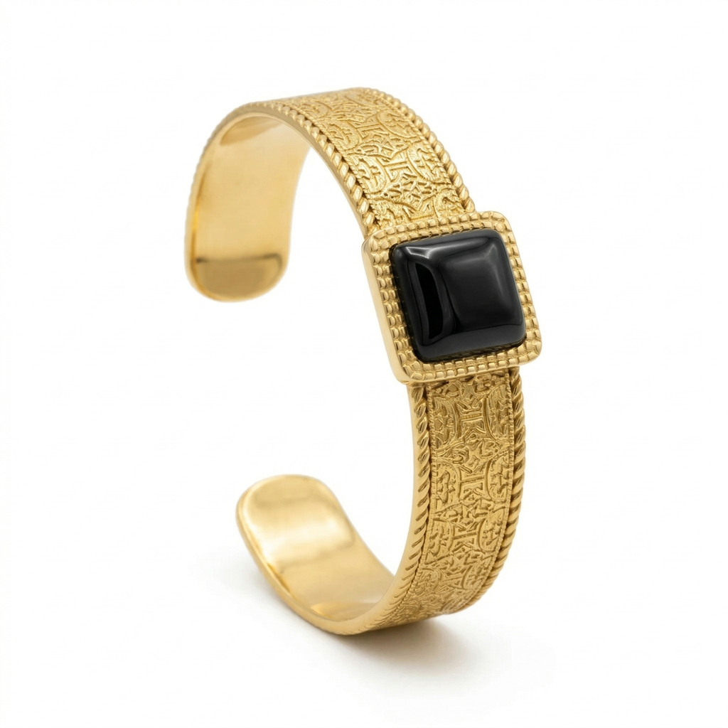 Bracelet large en acier plaqué or 18 carats, orné d'une pierre noire rectangulaire et d'une gravure.