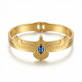Brazalete rígido de acero bañado en oro de 18K con diseño de ave de alas extendidas y piedra central azul, fabricado en España.