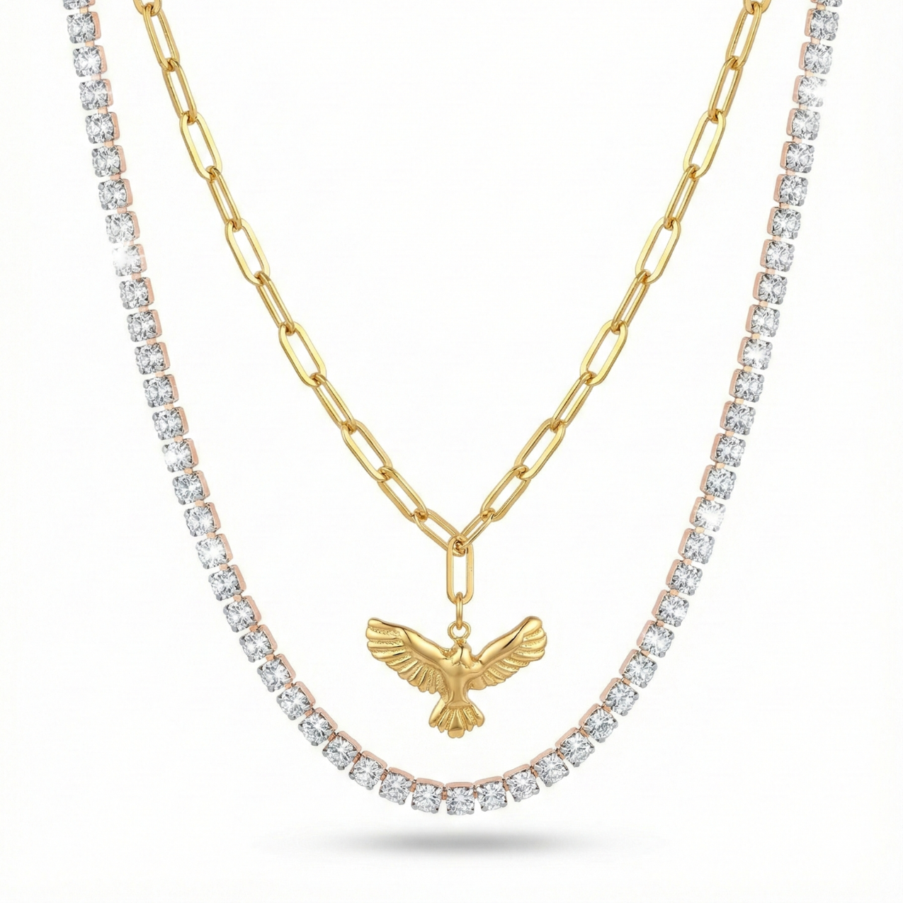 Set de collares de mujer superpuestos. Incluye una cadena tennis con brillantes y un collar de eslabones de 100% acero bañado en oro 18K con colgante de pájaro. Joyería hecha en España.