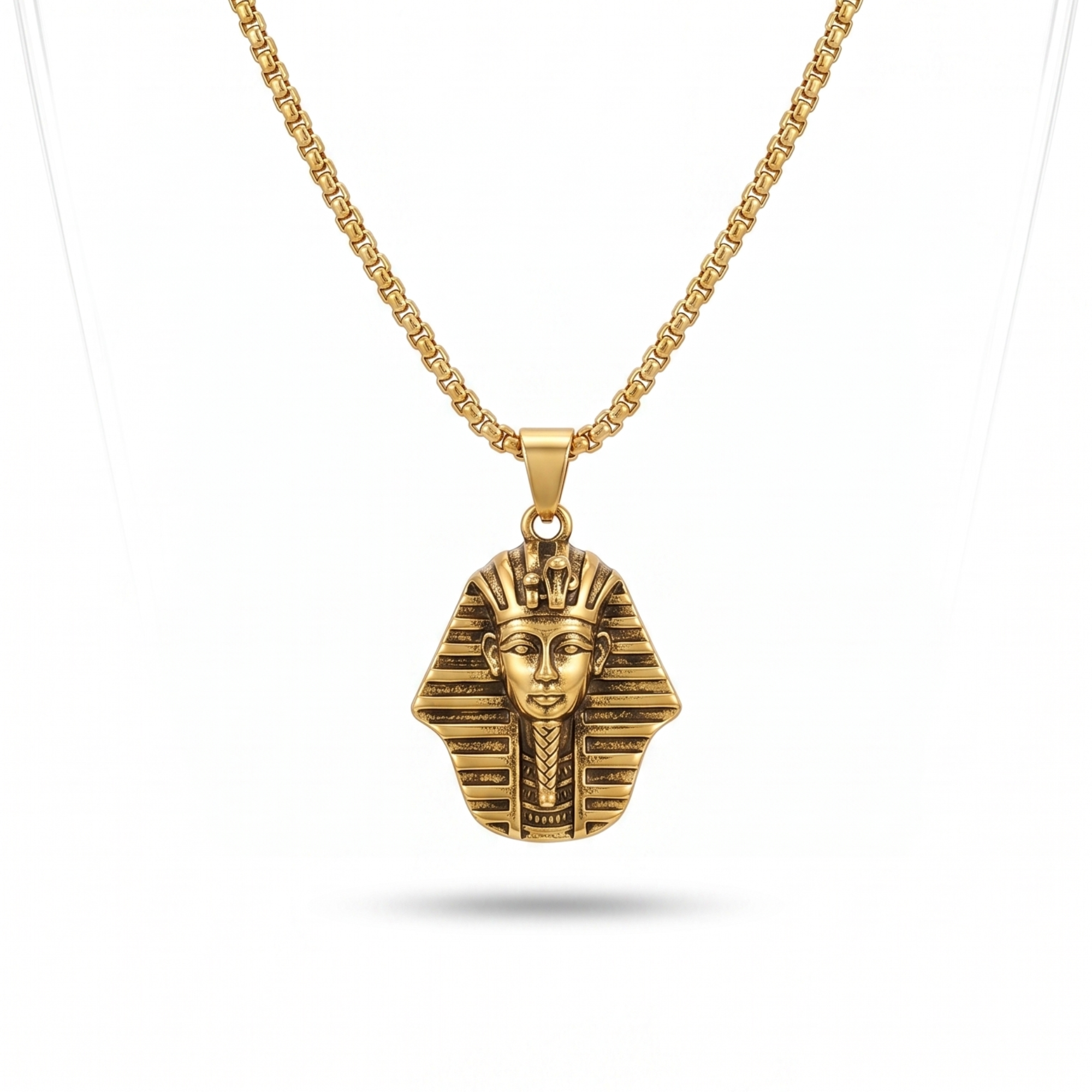 Collar de cadena dorada con colgante de cabeza de faraón egipcio en baño de oro de 18k, fabricado en España, sobre soporte de joyería.