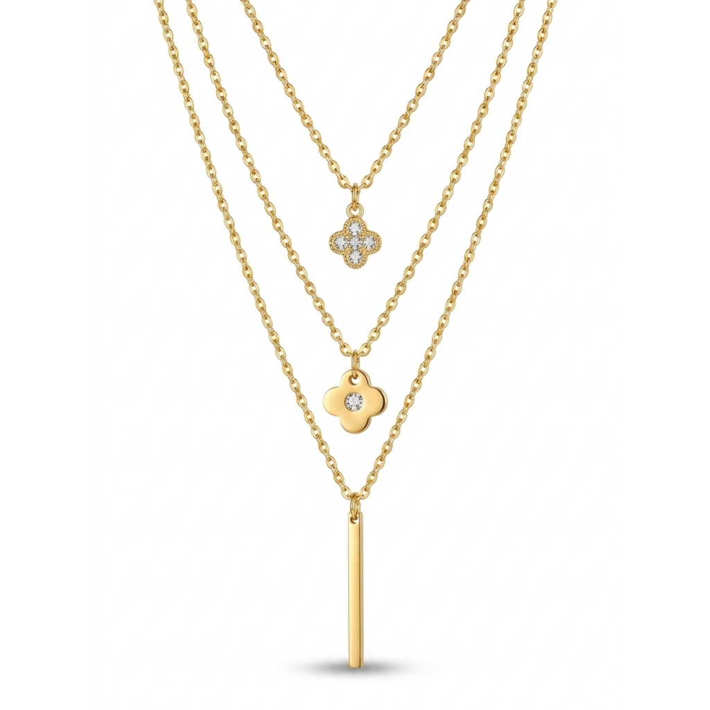 Collar de tres capas bañado en oro de 18k con dijes de tréboles de cuatro hojas con circonitas brillantes y una barra geométrica colgante, sobre fondo blanco de catálogo.