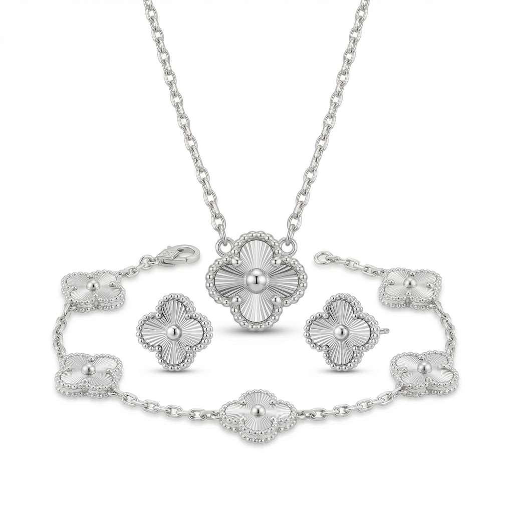 Conjunto de joyas de acero plateado que incluye collar, pulsera de cinco tréboles y pendientes con diseño de trébol grabado estilo guilloché sobre fondo blanco.