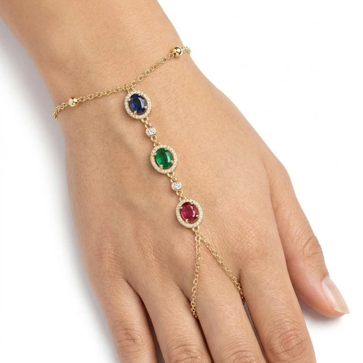 Pulsera de mano estilo hand chain bañada en oro de 18k PVD con cristales ovalados azul zafiro, verde esmeralda y rojo rubí, hecha en España.