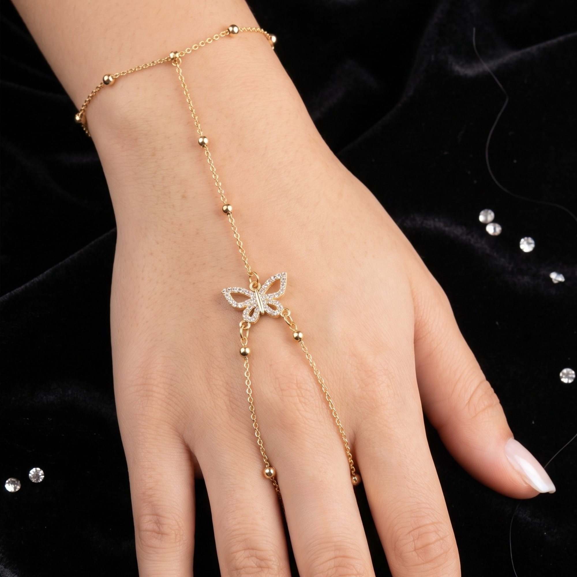 Elegante pulsera de mano bañada en oro de 18 quilates, con delicada cadena de esferas y un motivo central de mariposa engastada con circonitas brillantes.