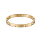Pulsera Love rígida de acero inoxidable 100% bañada en oro de 18K (18K Gold Plated) con incrustaciones de cristales, hecha en España, sobre una mesa frente a un teclado de ordenador.