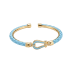 Pulsera rígida con baño de oro de 18K, trenzado azul cielo y cierre de herradura con circonitas, hecha en España.