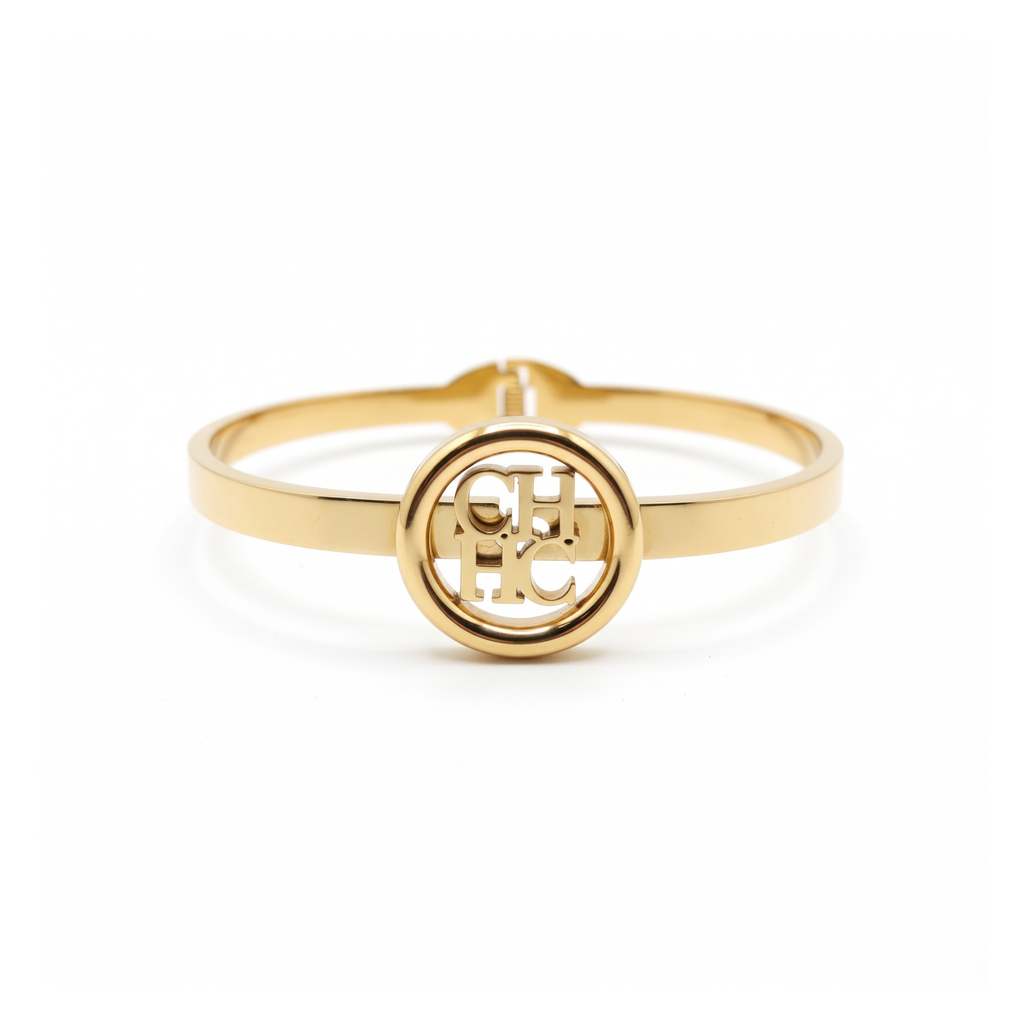 Pulsera rígida tipo bangle de acero inoxidable bañada en oro 18k con medallón central de monograma circular calado hecha en España.
