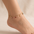 Tobillera de cadena fina de acero con baño de oro de 18K, adornada con charms colgantes de cristales de colores arcoíris y símbolos dorados, hecha en España.