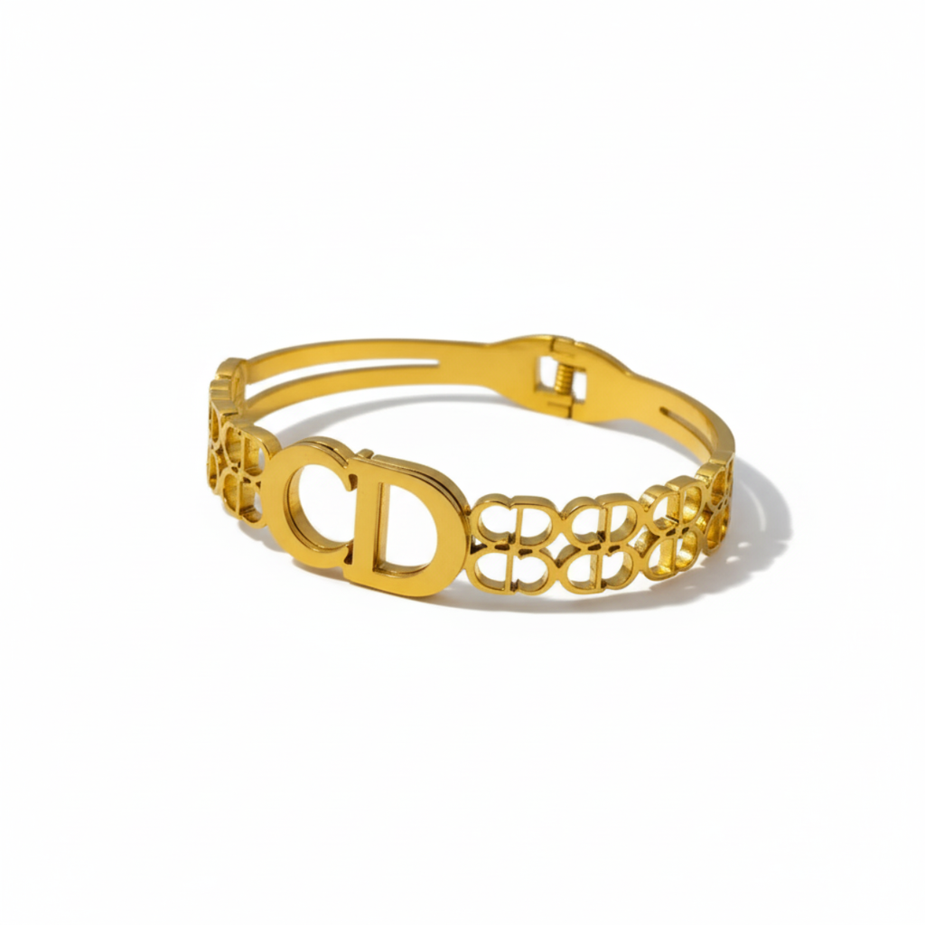 Bracelet rigide en acier plaqué or 18 carats, orné d'une double lettre et d'un motif ajouré.